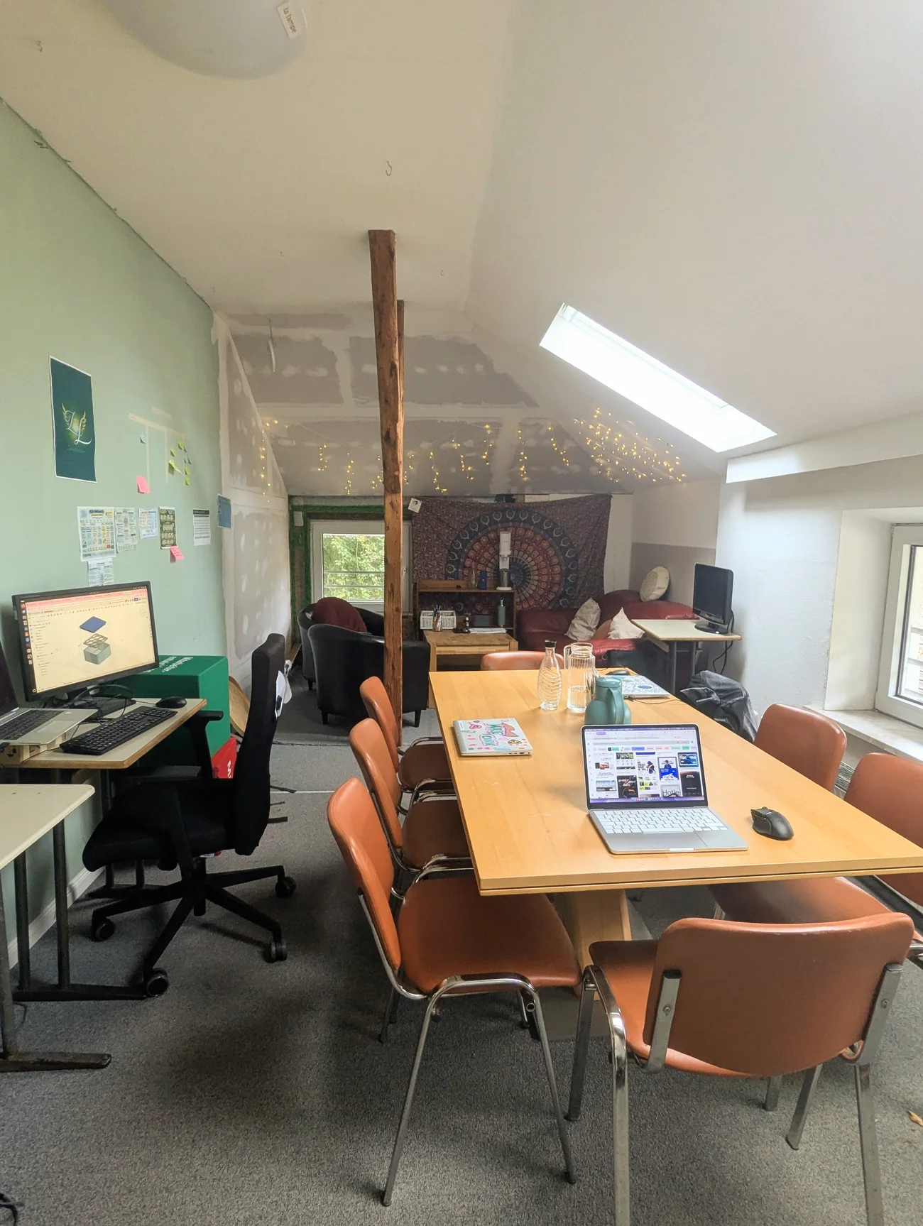 Blick in den Zukunftslabor-Raum mit gemeinsamem Arbeitstisch, Computerarbeitsplätzen und Sitzbereich